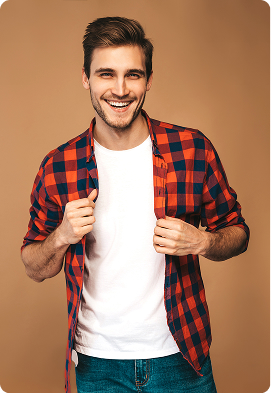 Man wearing a red and blue plaid shirt over a white t-shirt stands against a warm brown background with rounded corners. He is holding the open shirt with both hands, creating a casual and confident mood. The setting feels modern and minimalistic with no visible text.