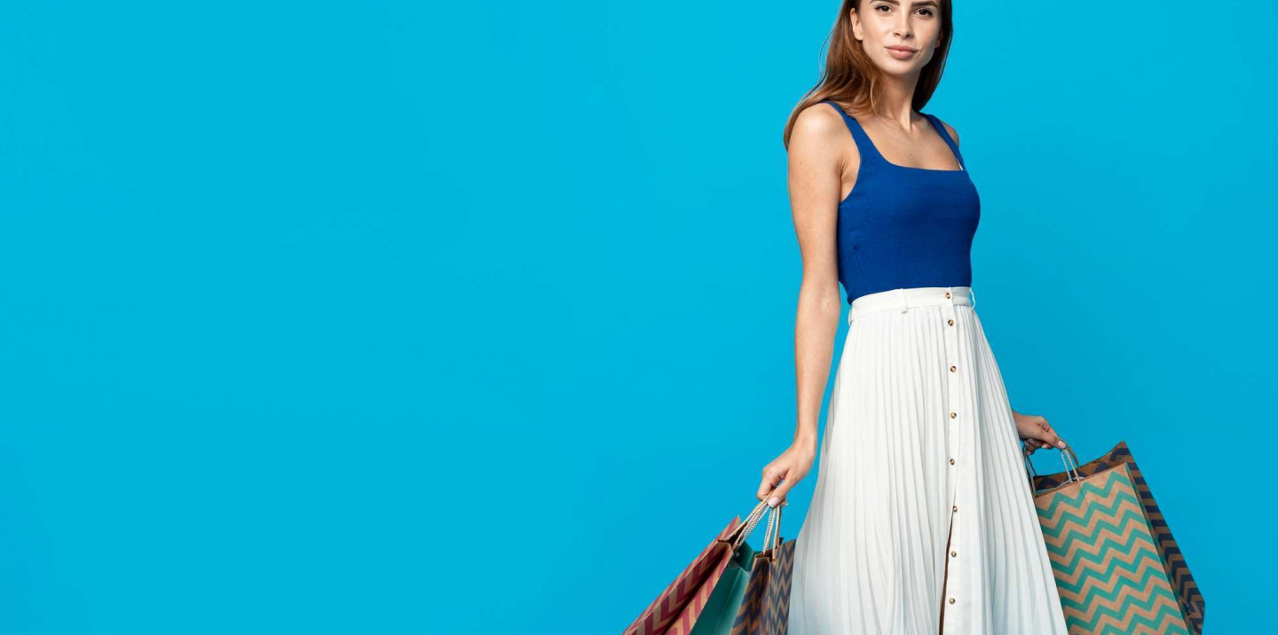 A stylish young woman wearing modern casual clothing poses confidently in a bright, minimalistic studio setting with soft natural light. The environment feels fresh and inviting, conveying a sense of optimism and contemporary fashion.