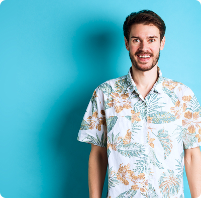 Man wearing a white Hawaiian shirt with orange and green floral patterns stands against a bright blue background with rounded corners. The setting feels fresh and summery, conveying a relaxed and cheerful mood.